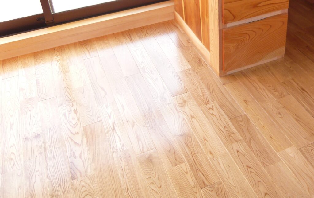 美しい木目が際立つ無垢材のヒノキフローリングと、丁寧な納まりが施された巾木と家具の接合部。