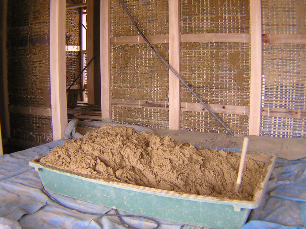 伝統工法による竹小舞（たけこまい）の編み込みと、職人の手仕事による荒壁（あら壁）塗りの工程。